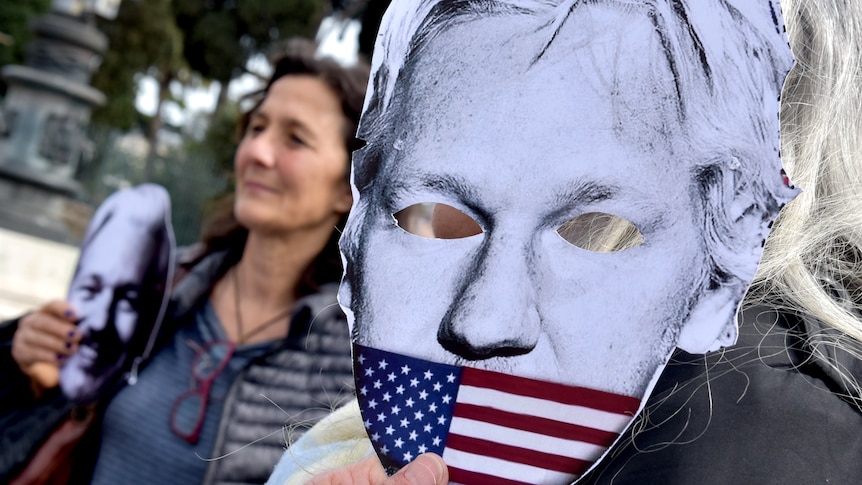 People hold a poster of Julian Assange's face