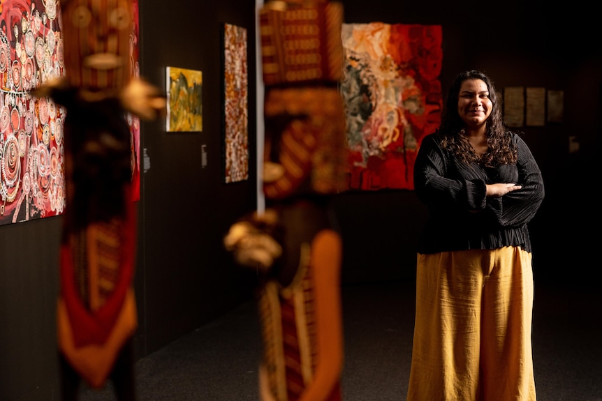 MAGNT curator Rebecca Raymond stands next to the artworks of several NATSIAA finalists.