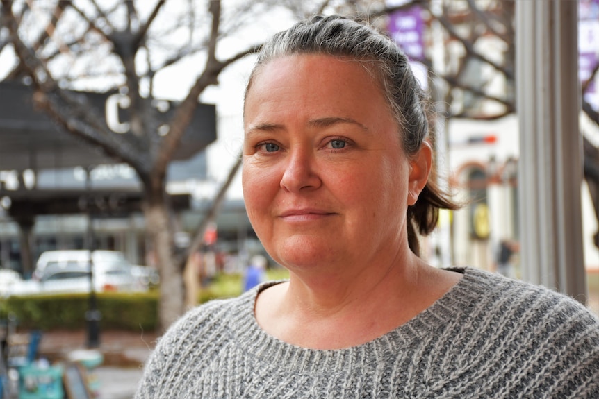 A woman standing in Dubbo's main street smiles at the camera.