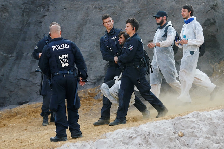 Police officers detain an environmental activist