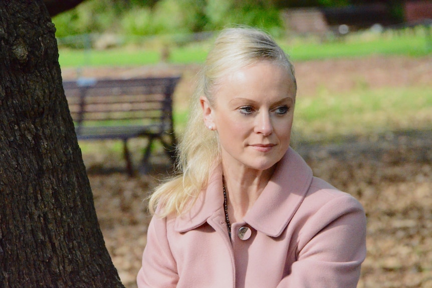 Jessica staring off to the right side, sitting on a bench at a park.