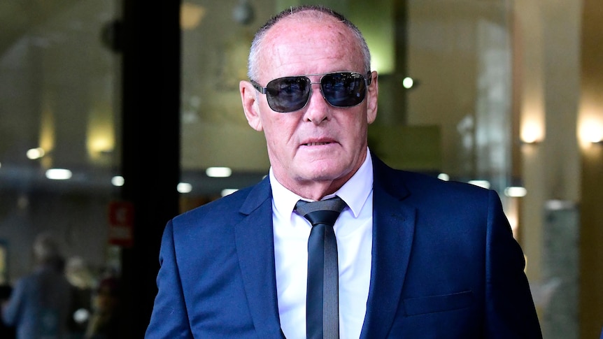 a man wearing dark glasses leaving court