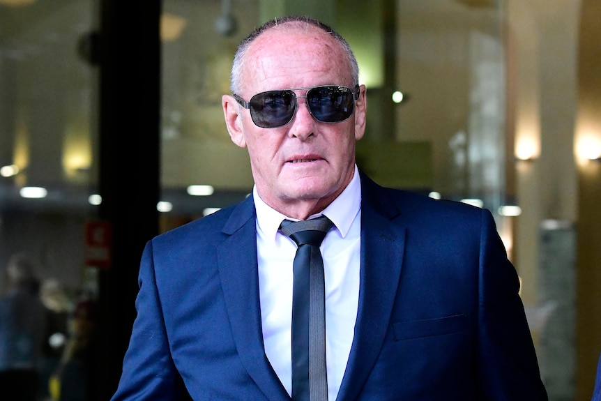 a man wearing dark glasses leaving court