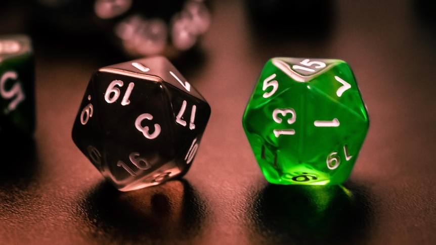 A close-up shot of to Dungeons and Dragos multi-sided dice, one black and one green, one a dark table