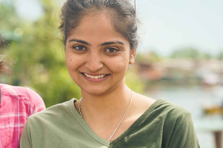 A close up of a smiling woman wearing a green shirt.