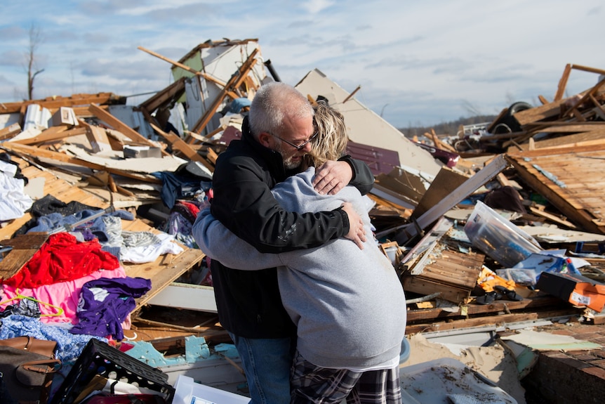 Mężczyzna przytula swoją córkę w gruzach ich domu