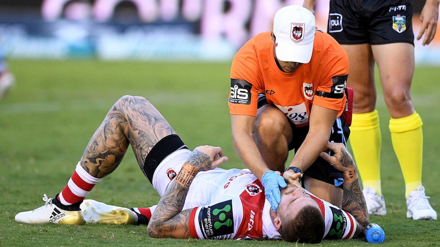 Josh Dugan receives medical attention on the field.