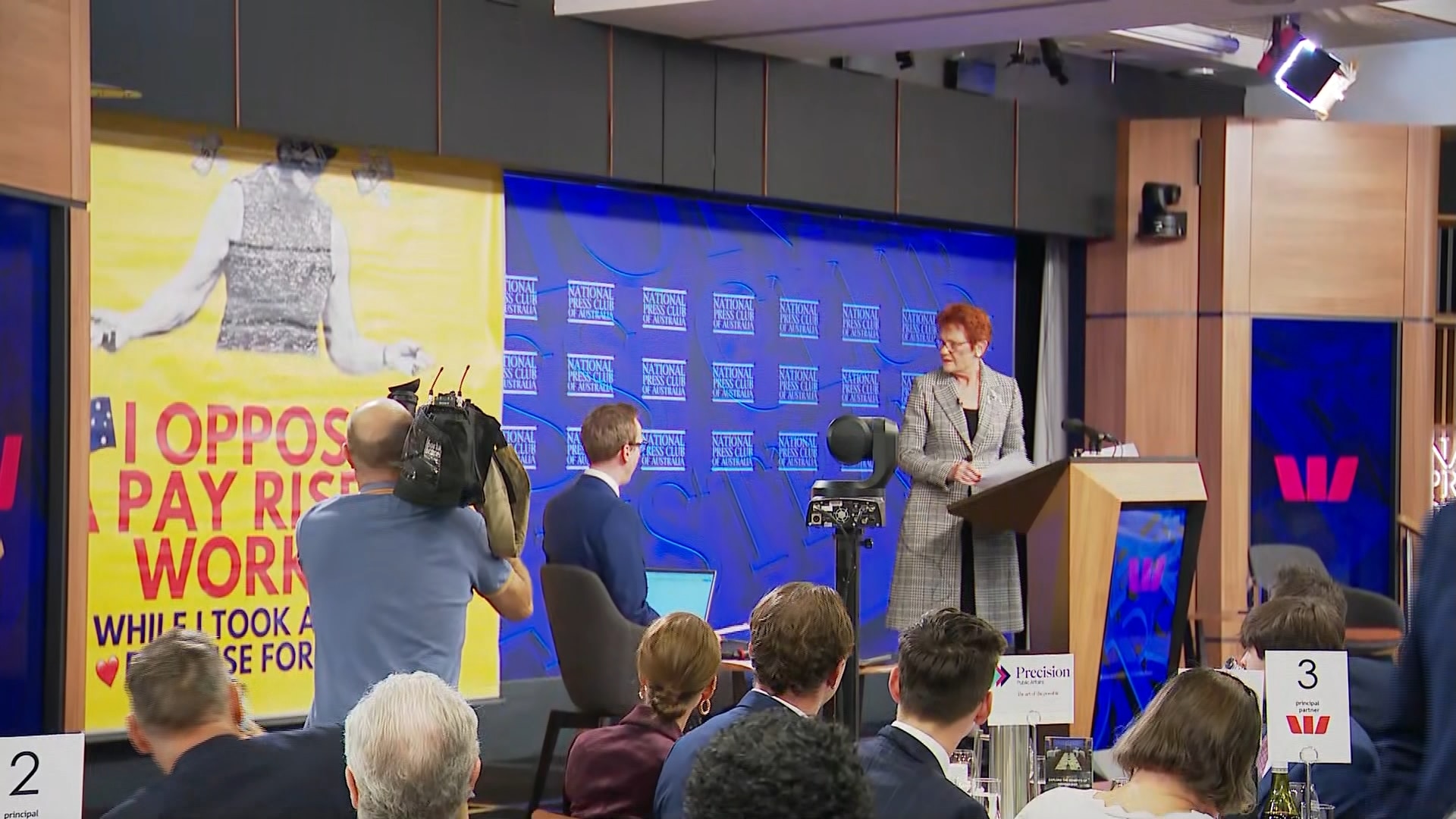 Protest banner coming down behind Pauline Hanson. 