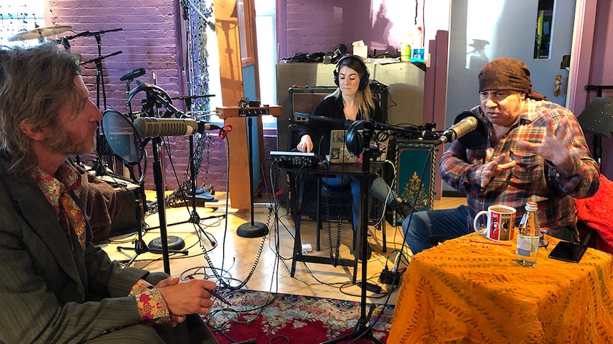 Tim Rogers, Steven Van Zandt and a female producer sit in a recording studio with microphones