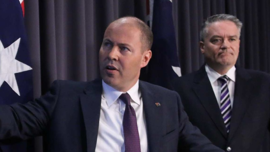 The Treasurer points to a screen showing net debt declines as the Finance Minister looks on.