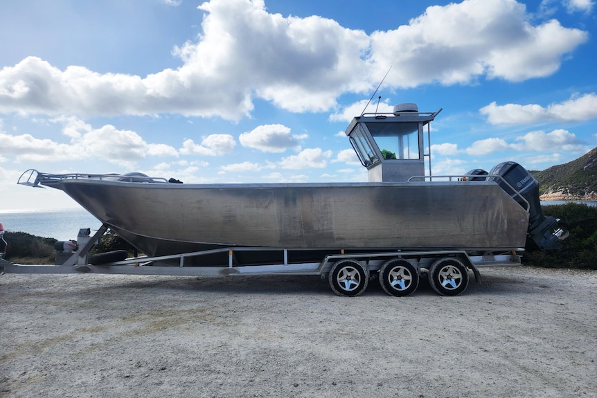 A 10-metre bare-metal boat with small cabin on the back of a boat trailer.
