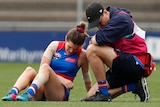 Kirsten McLeod is tended to by a trainer while she sits on the turf at Whitten Oval
