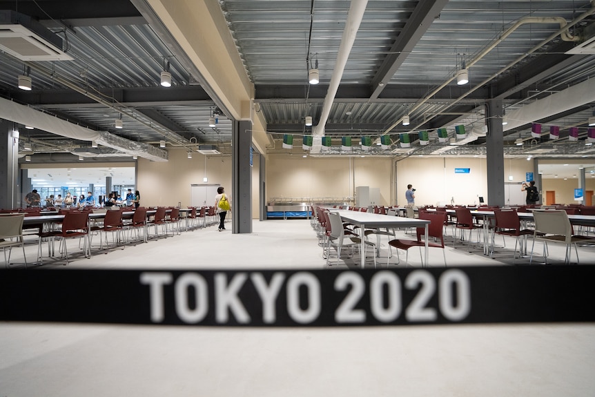 The Tokyo Olympics athletes village main dining area behind a sign saying 'Tokyo 2020'