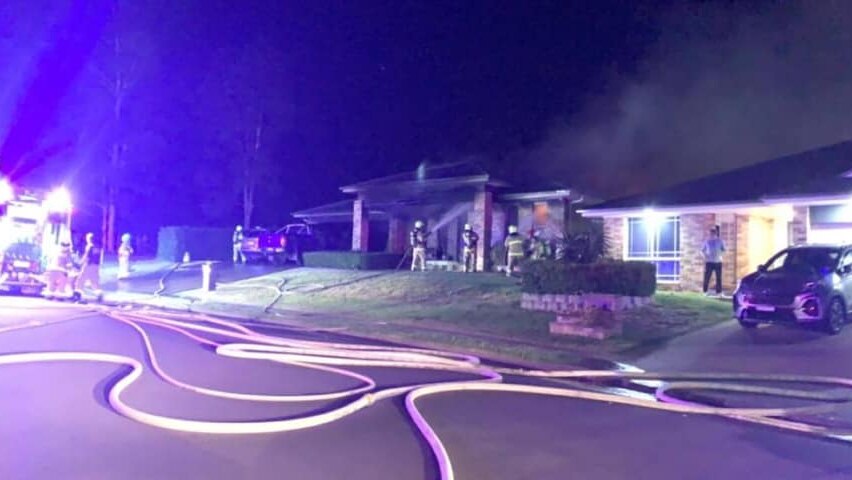 Firefighters with hoses in hand on scene at a suburban house fire