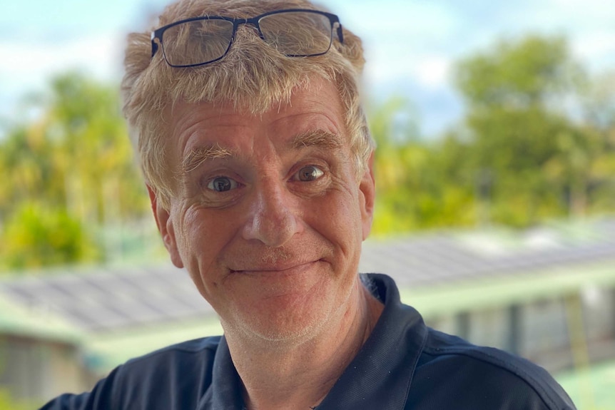 portrait of a man smiling at camera blurred background glasses on head