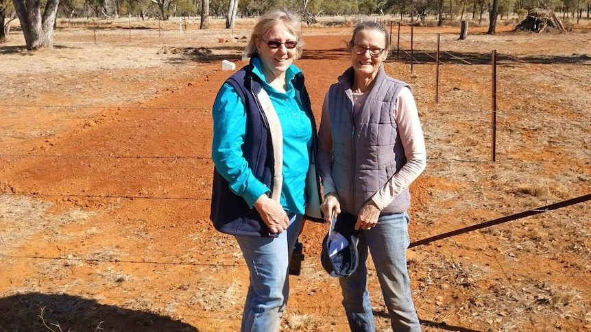 Two women stand in the outback in the Langlo Cemetery.