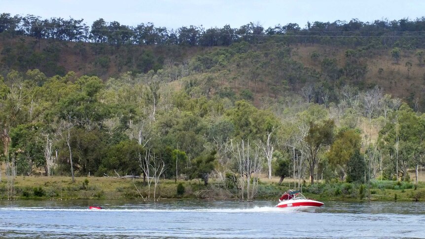 A red and white coloured boat drags an inflatable tyre across the waters of Paradise Dam.