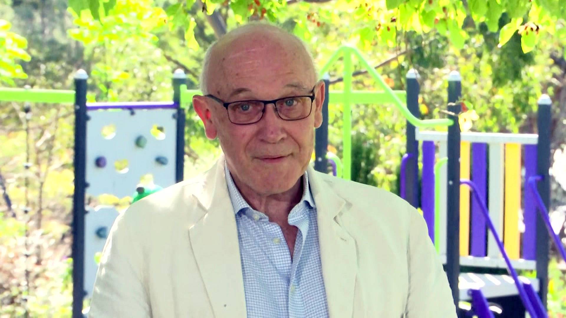 a man wearing glasses speaking to the media outdoors