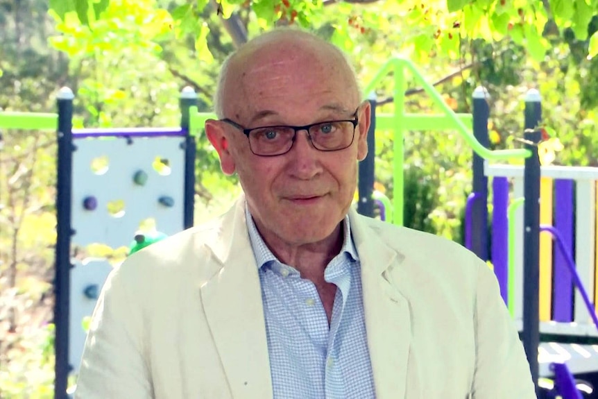 a man wearing glasses speaking to the media outdoors