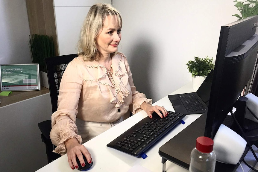 A woman at a desk in front of a desktop computer