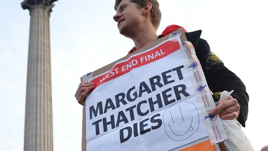A man holds a placard announcing the death of Margaret Thatcher