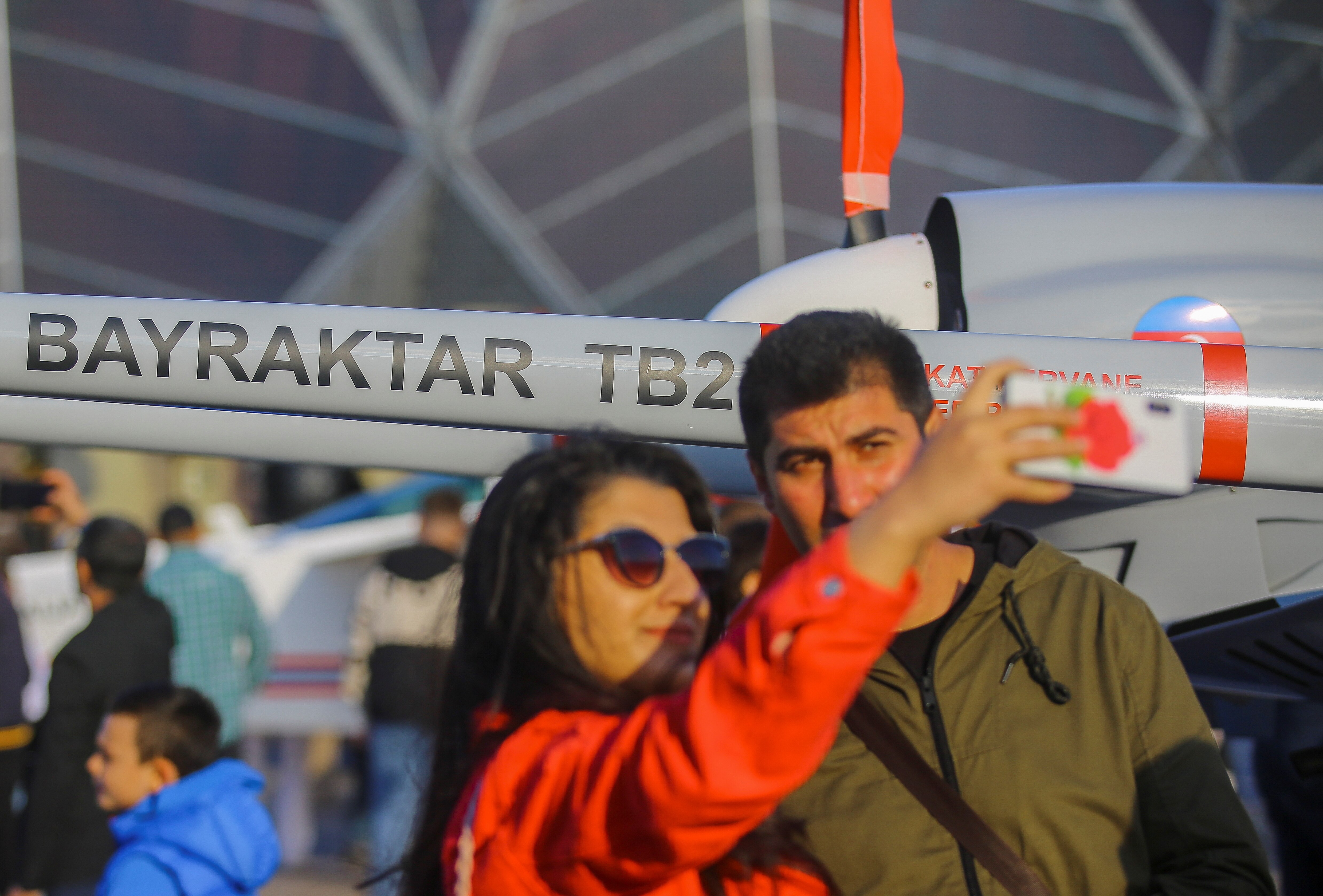 A woman takes a selfie with a man in front of a small plane 