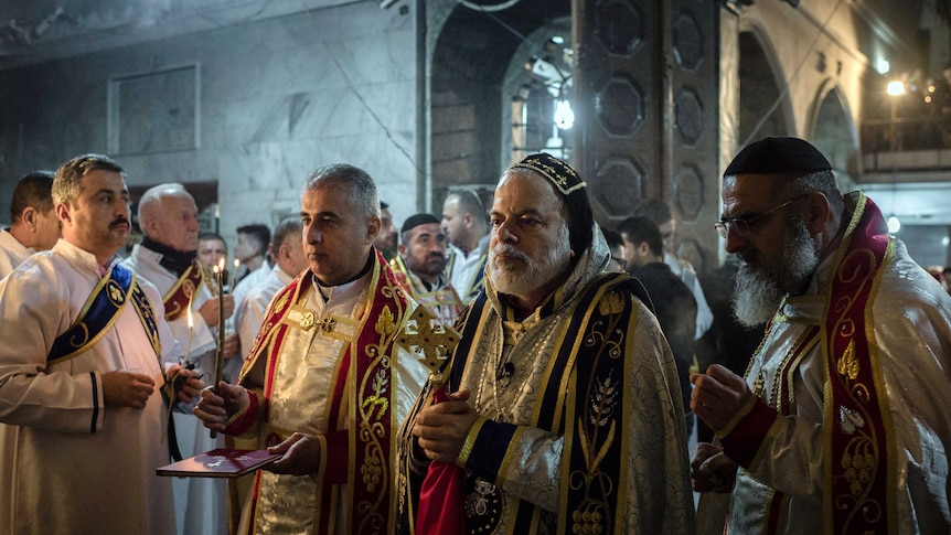 Priests hold candles as they lead midnight mass at the Assyrian Orthodox Church in Bartella, Iraq.