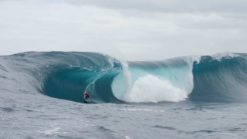 A woman surfs a huge wave