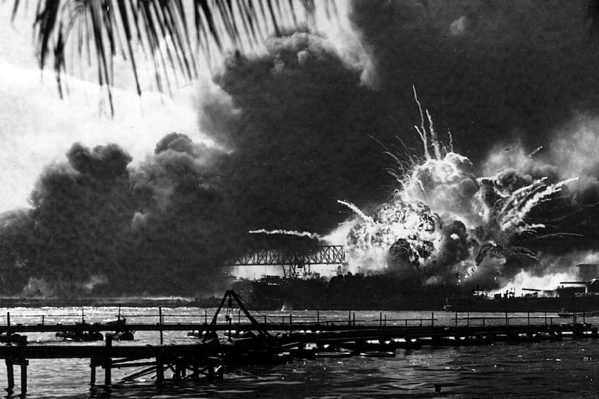 A 1940s black and white photo of a navy ship exploding.