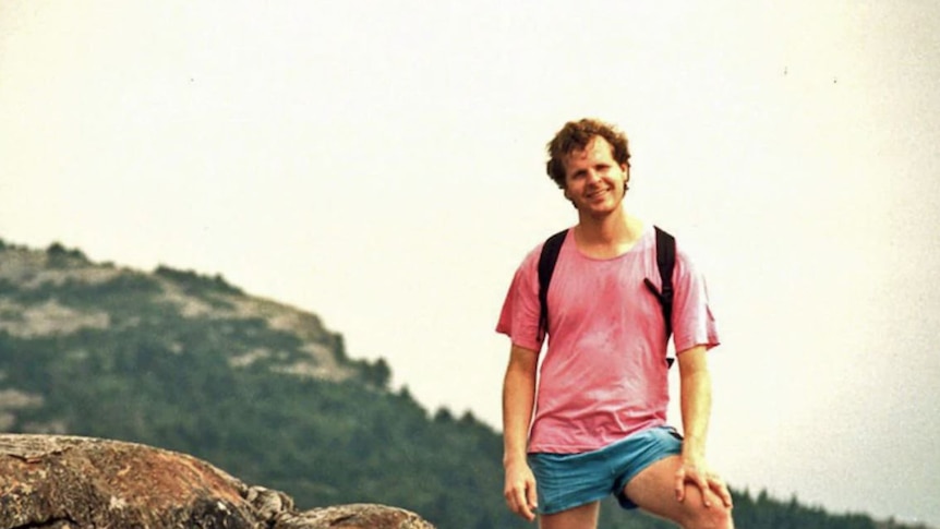 a man looking and smiling and standing on top of a cliff