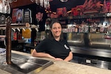 Alison Avron is wearing a black t-shirt as she leans on the bar behind beers taps in the great club marrickville