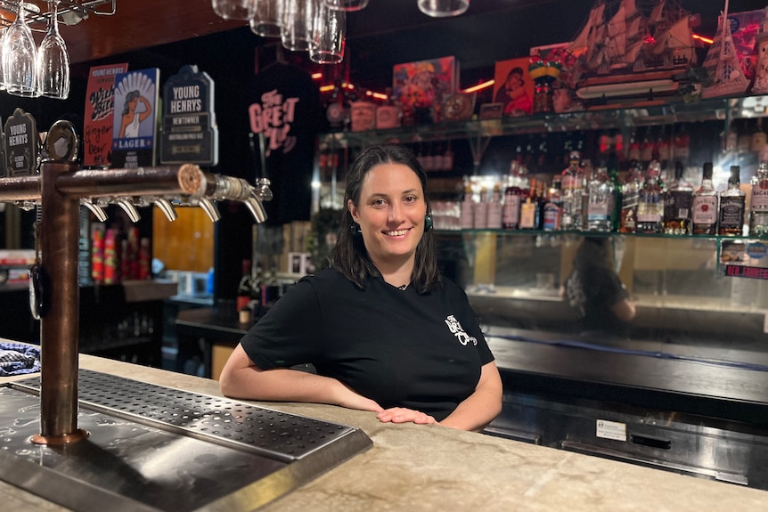 Alison Avron is wearing a black t-shirt as she leans on the bar behind beers taps in the great club marrickville