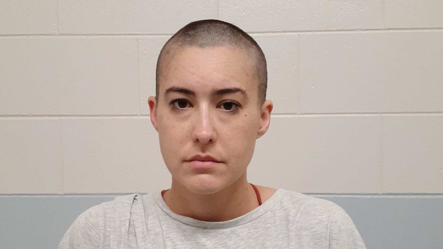 Police mugshot of woman with shaved head.