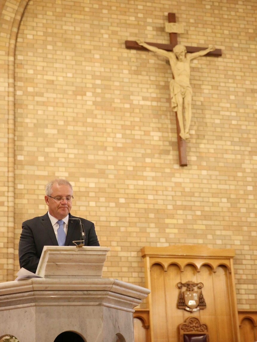 Scott Morrison speaks at a church pulpit with Jesus on a crucifix above him