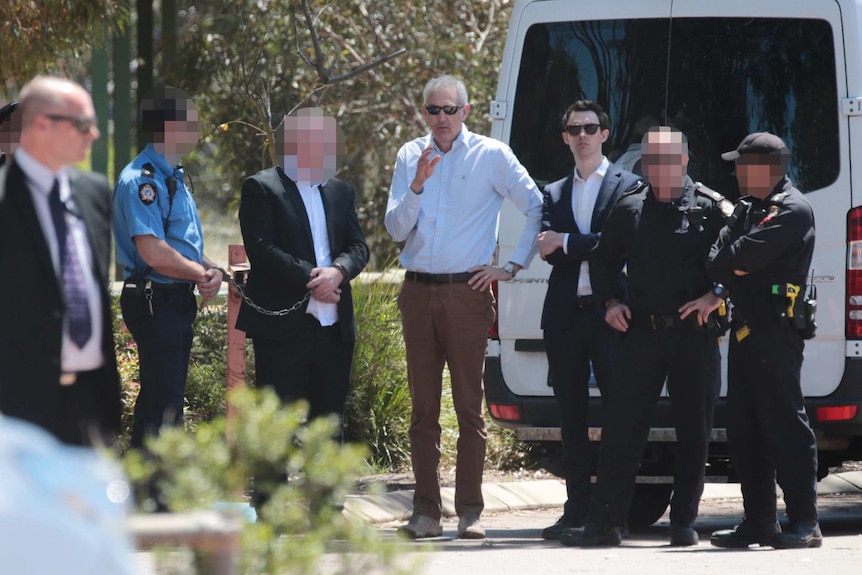 A hand-cuffed Francis John Wark with his lawyer Darryl Ryan and police in the WA town of Moora.