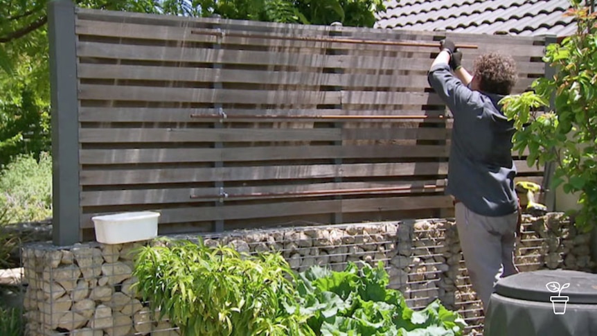 Man attaching rails to fence in garden