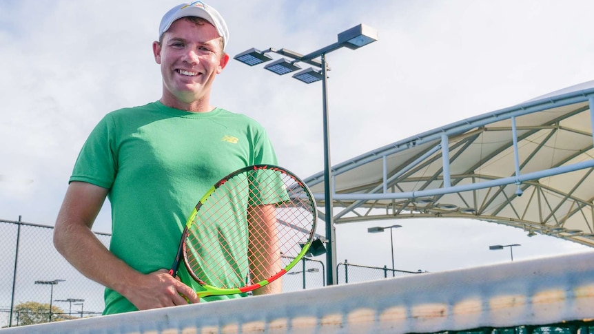 Man holds a tennis racquet on a tennis court.