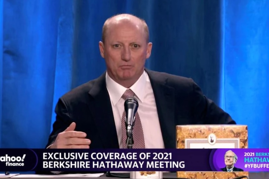 A man in a business suit sitting at a desk about to address shareholders.