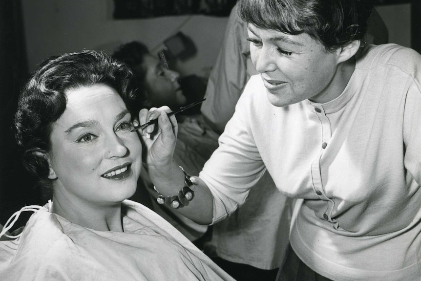 A photo shows a makeup artist applying mascara to TV host Joy Wren