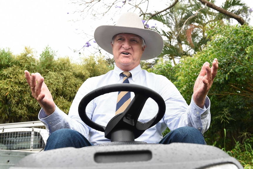 Akubra-clad Bob Katter on a ride-on mower