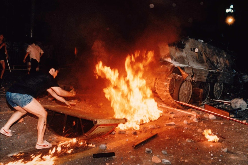 A student protester puts barricades in the path of a burning armoured personnel carrier during the Tiananmen Square massacre.
