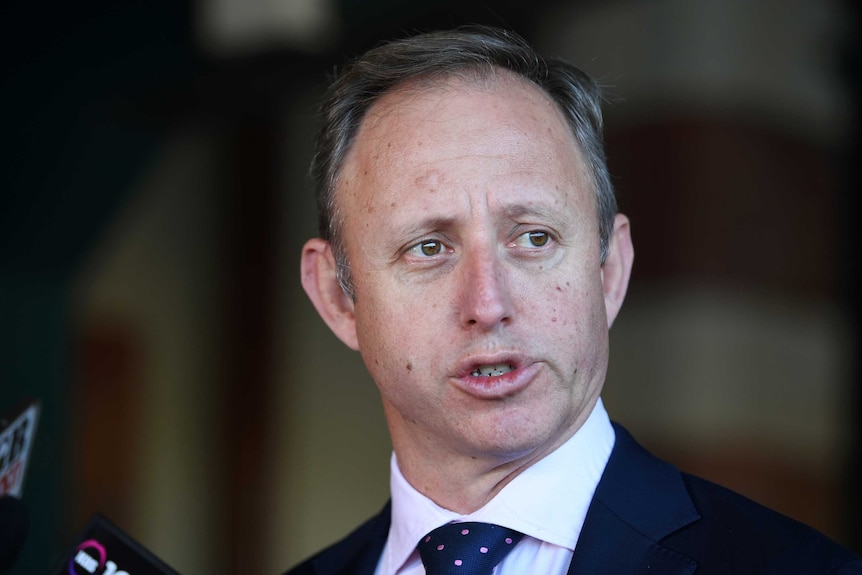 a man in a suit fronting a press conference