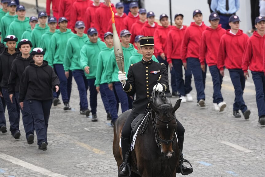A man dressed in black riding a dark brown horse in a parade