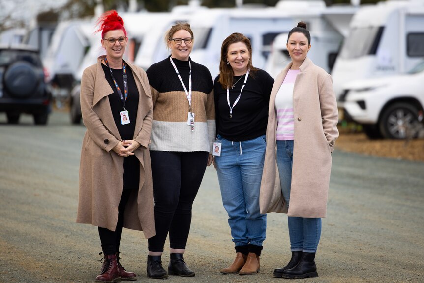 Four female Anglicare workers standing in front of a row of cars at the recovery centre.