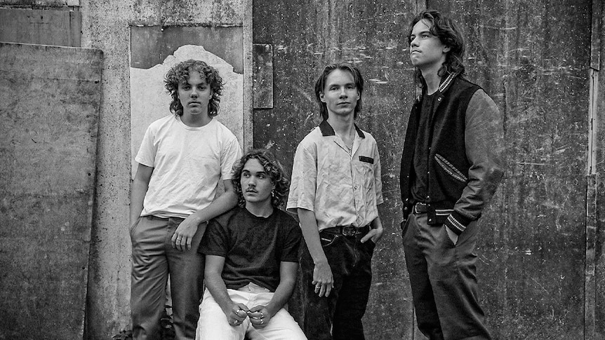 The four members of The Rions, four young men with long hair, stand looking away from the camera in black and white.