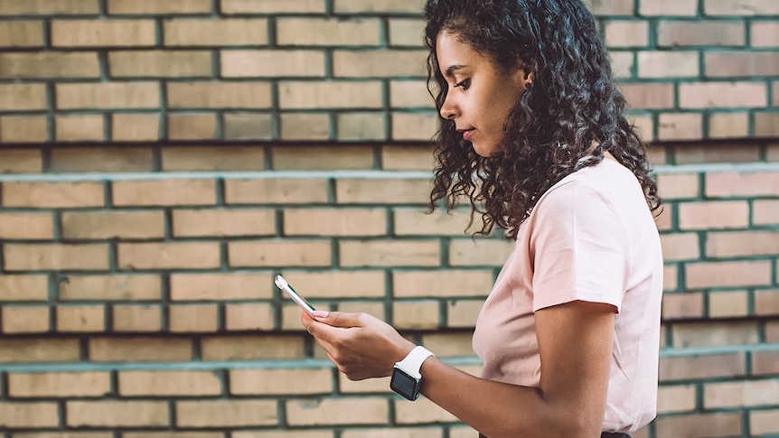 woman walking along looking at her phone