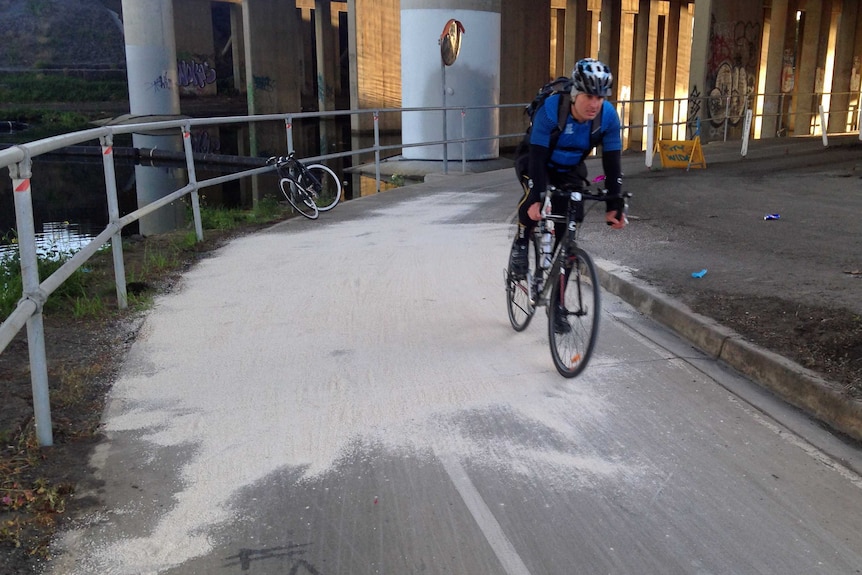 A cyclist rides over a sand-covered bike trail.