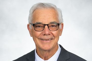 a man with gray hair and glasses wearing a suit.