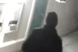 A grainy CCTV still shows what appears to be a man dressed in black walking away from camera