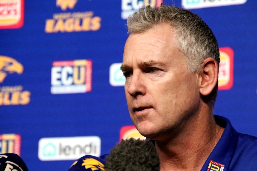 Foto close-up Adam Simpson di depan spanduk West Coast Eagles pada konferensi pers.